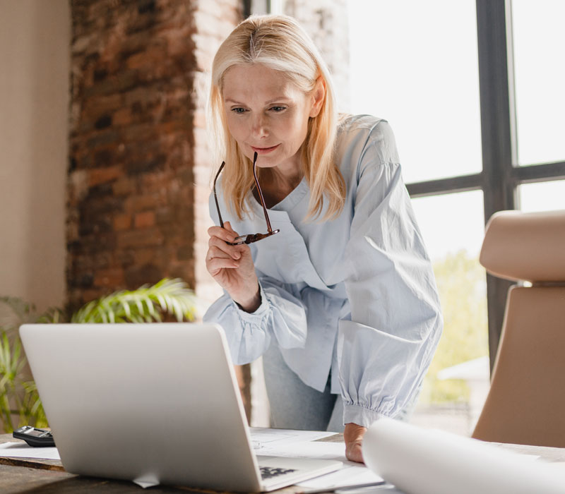 A business woman standing while viewing a laptop screen on a desk